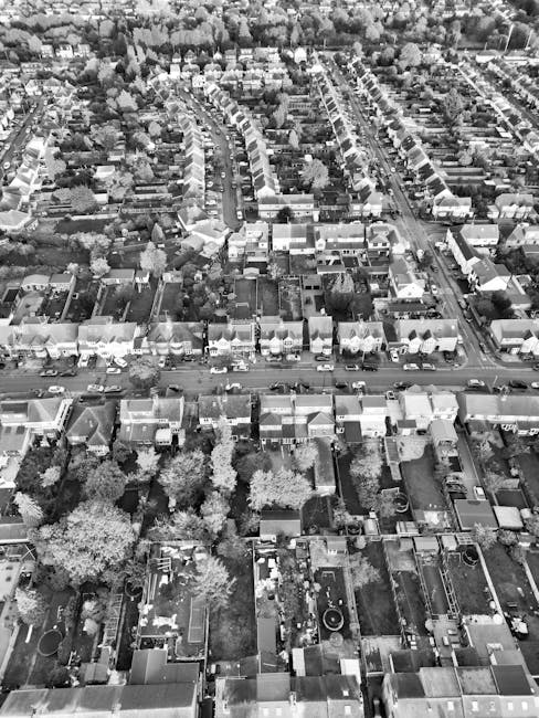 An aerial black-and-white photograph of a residential area in Erith, showcasing closely packed houses with pitched roofs, narrow streets, and gardens. The image highlights well-maintained lawns, some 